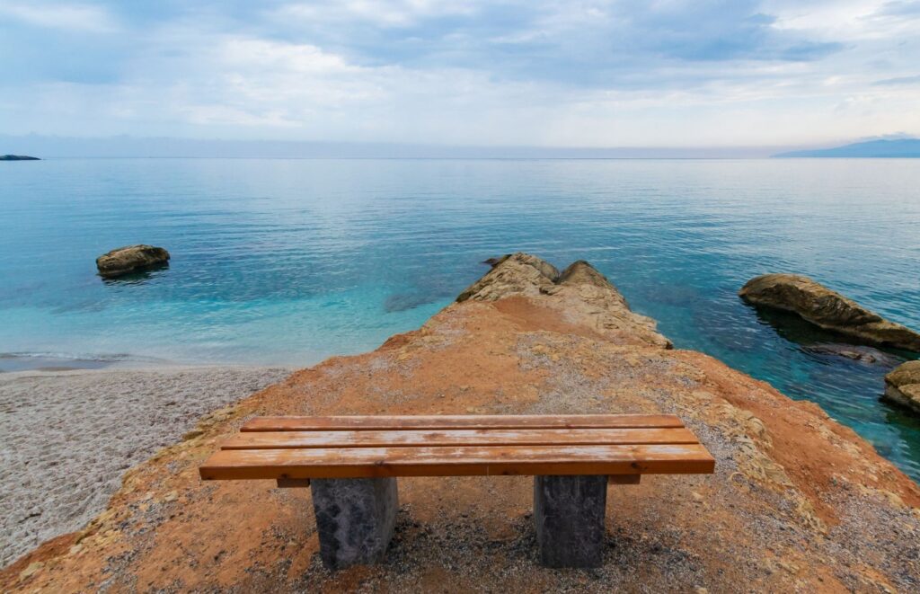 Solitary wooden bench overlooking the ocean representing space for grief and reflection in grief therapy