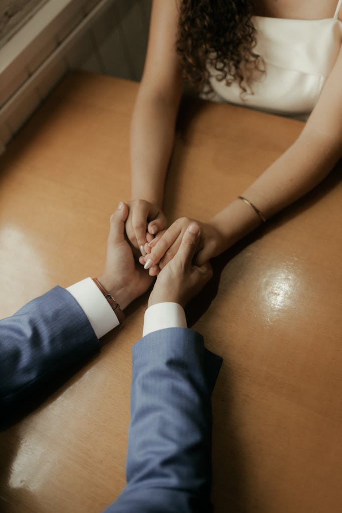 Close-up of a couple holding hands across a table, symbolizing love and connection.
